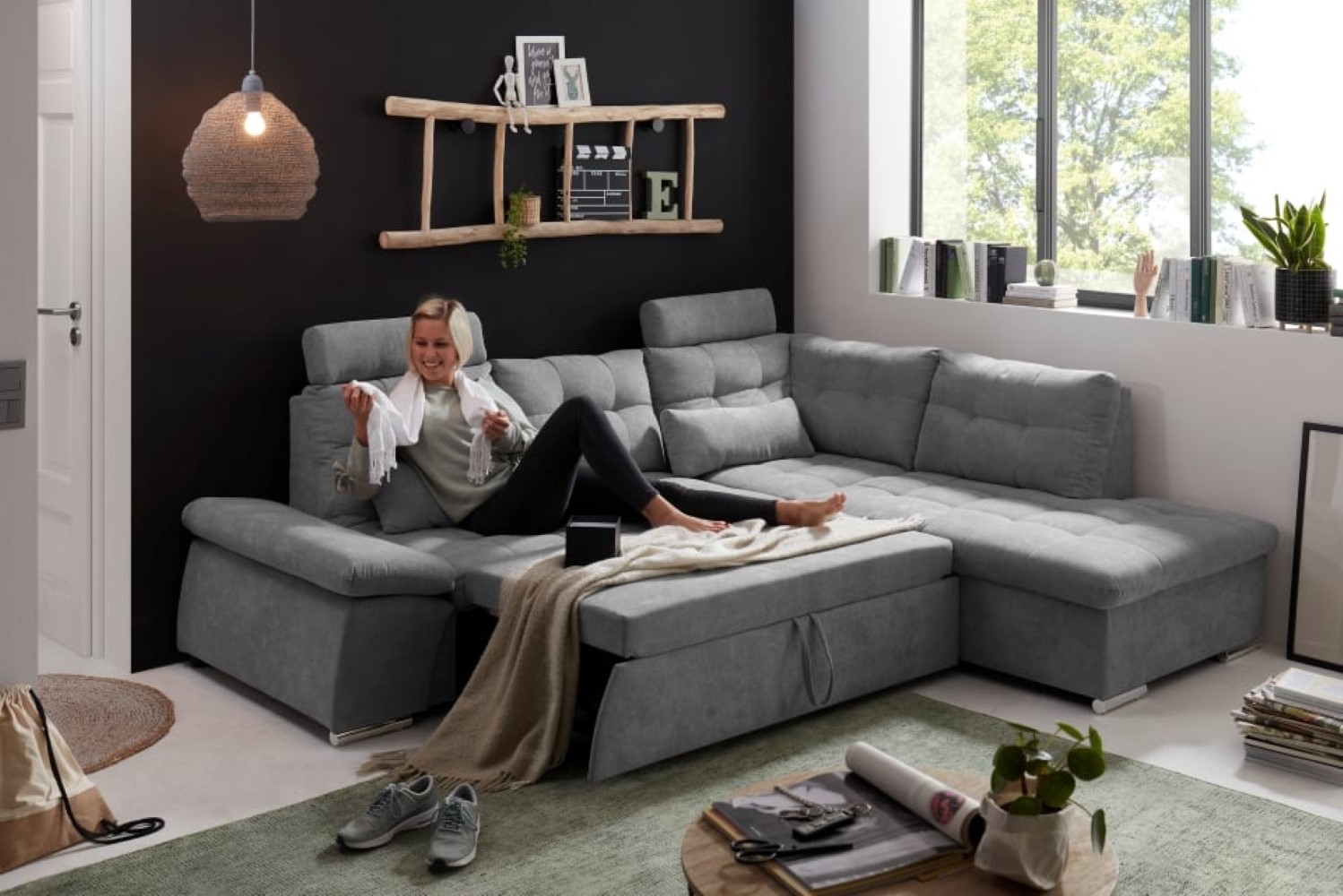 Nalo-2F-Rec_Uran-03-dark-grey_Milieu_Model Edles Dunkelgrau: Das Nalo Schlafsofa mit verstellbaren Armlehnen und Bettkasten